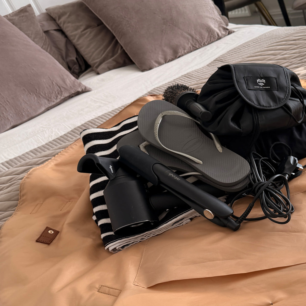 Black OYSTER lay-flat tote opened on a bed with gym clothing, towel and wash bag inside, showing its roomy design for carrying everyday workout essentials.