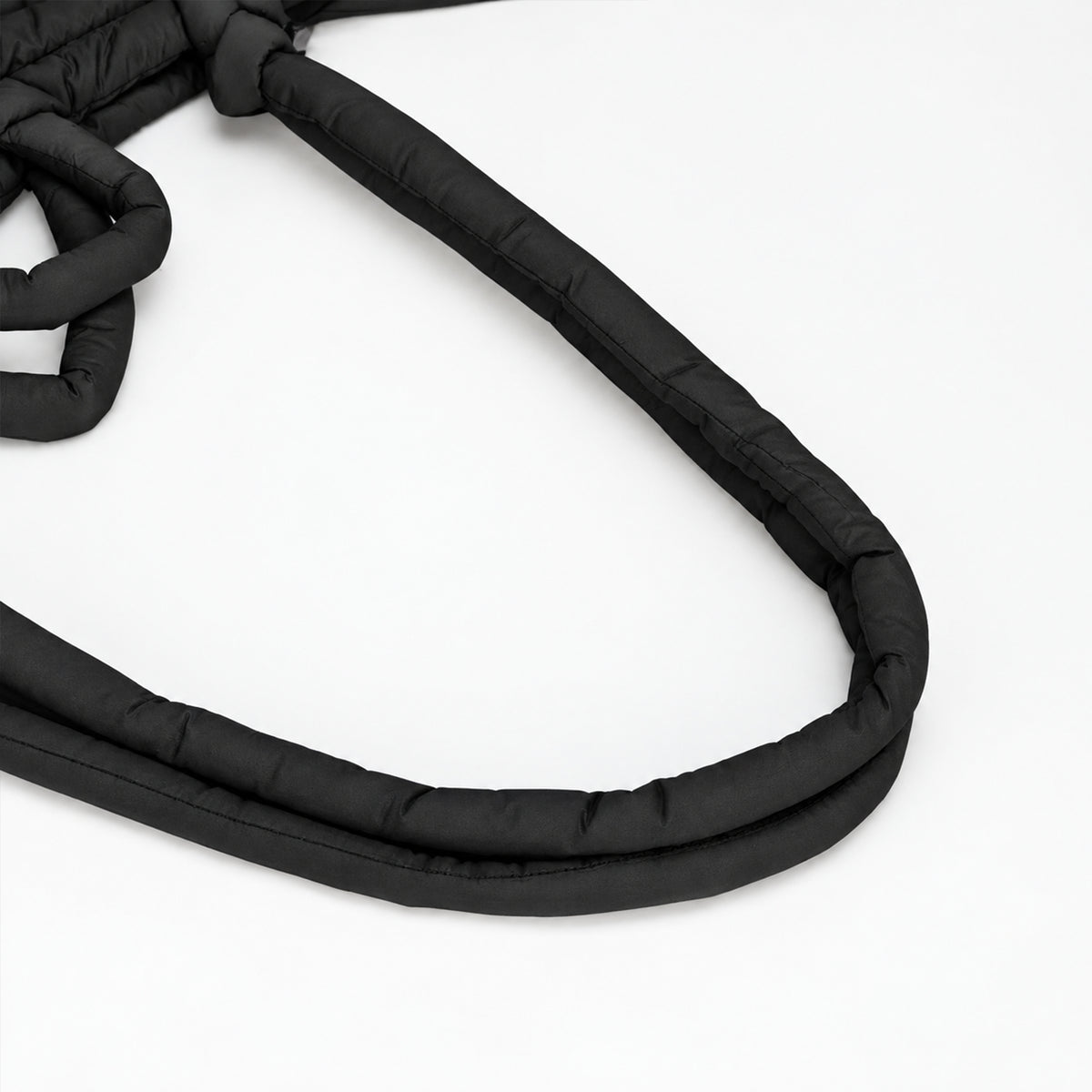 Close-up of the soft, curved padded shoulder strap on the black PUFFER Mini multiway tote bag, designed for comfortable everyday carrying.