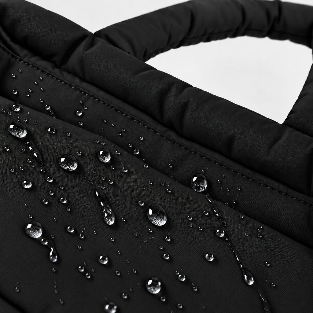 Water droplets beading on the black PUFFER Mini tote bag, showing its water-repellent fabric designed to help protect against light rain.