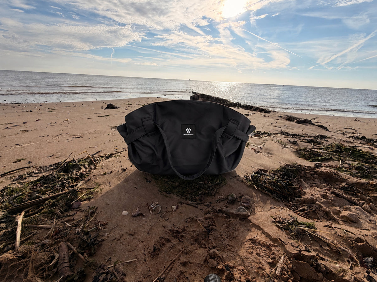 MOD LE MODE Oyster Lay-flat Tote Bag shown on the beach, highlighting its distinctive oyster shape and gathered sides.