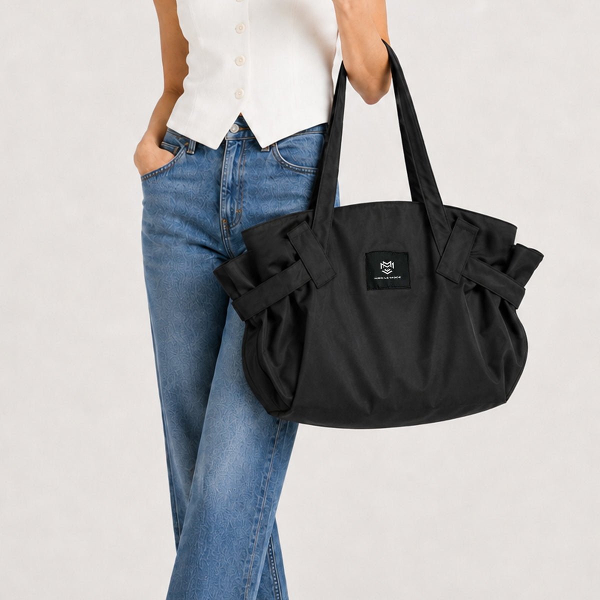 Model carrying the Black MOD-LE-MODE OYSTER lay-flat carry-all tote bag, wearing blue jeans and a white top