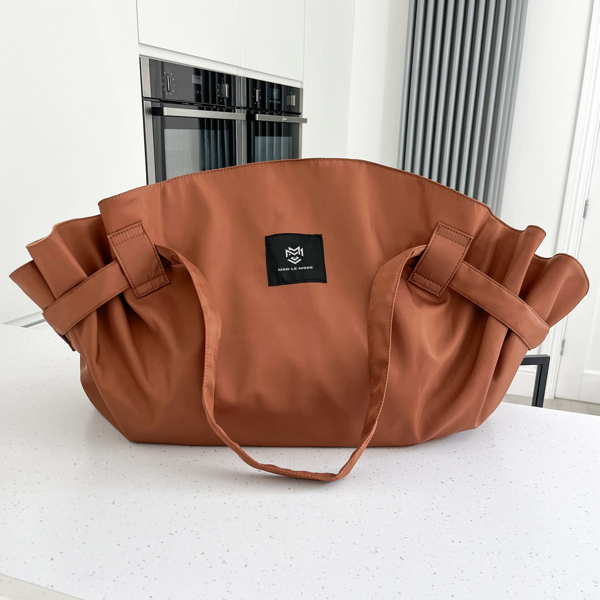 Cinnamon Brown MOD-LE-MODE OYSTER lay-flat carry-all tote bag with wide straps on a white kitchen countertop