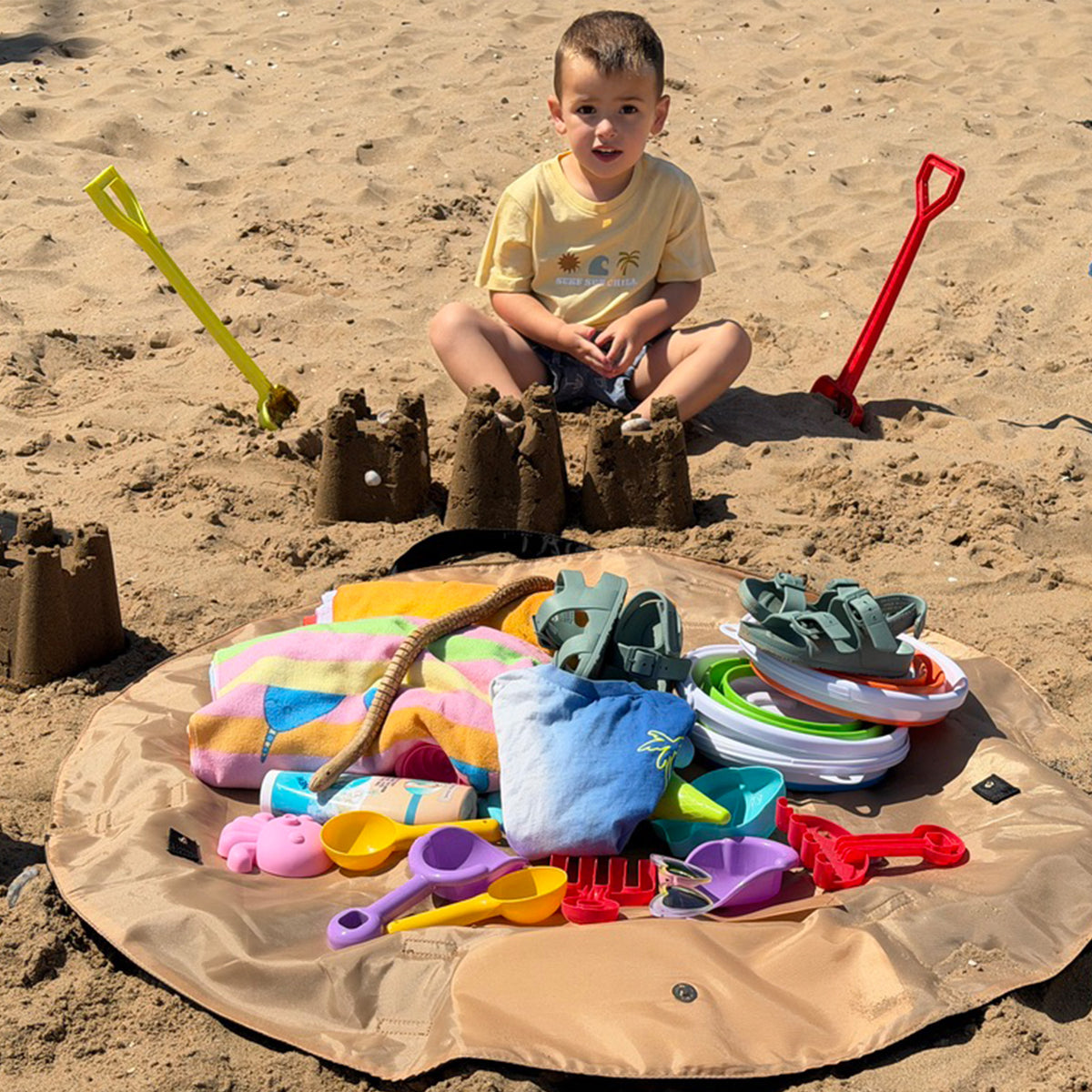 mod-le-mode oyster lay-flat tote bag packed with towels, beachwear and beach essentials on the beach